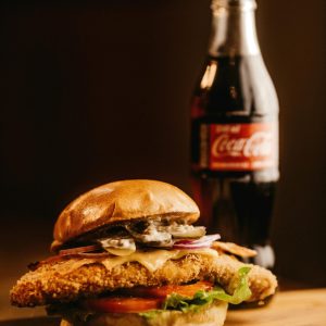Mouth-watering burger with a bottle of cola, perfect for fast food lovers.