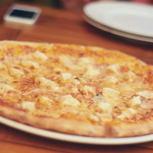 Close-up of a cheese pizza on a wooden table, ready to be served and enjoyed.